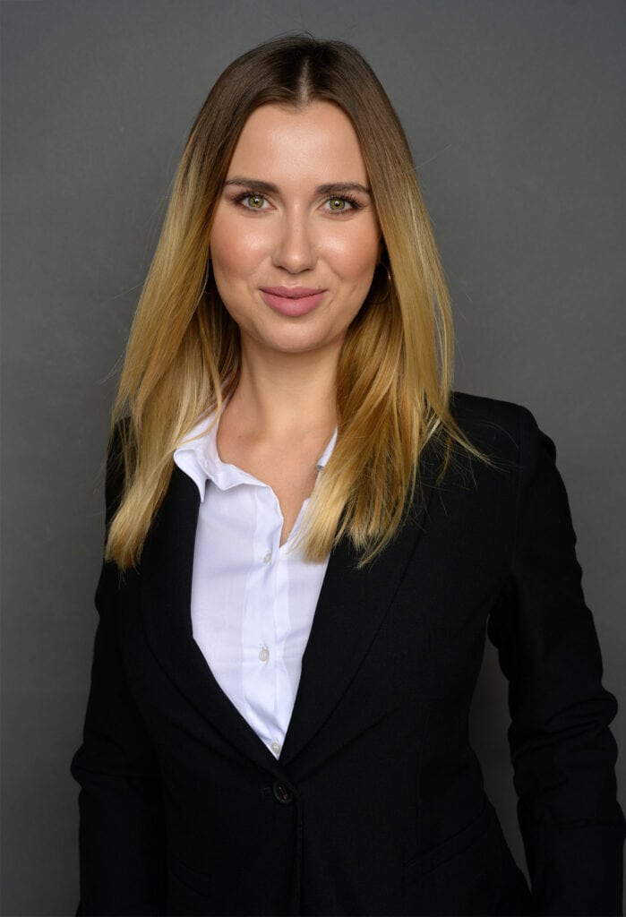 fotografia biznesowa młodej uśmiechniętej bizneswoman ubranej w garnitur w otoczeniu biznesowym
